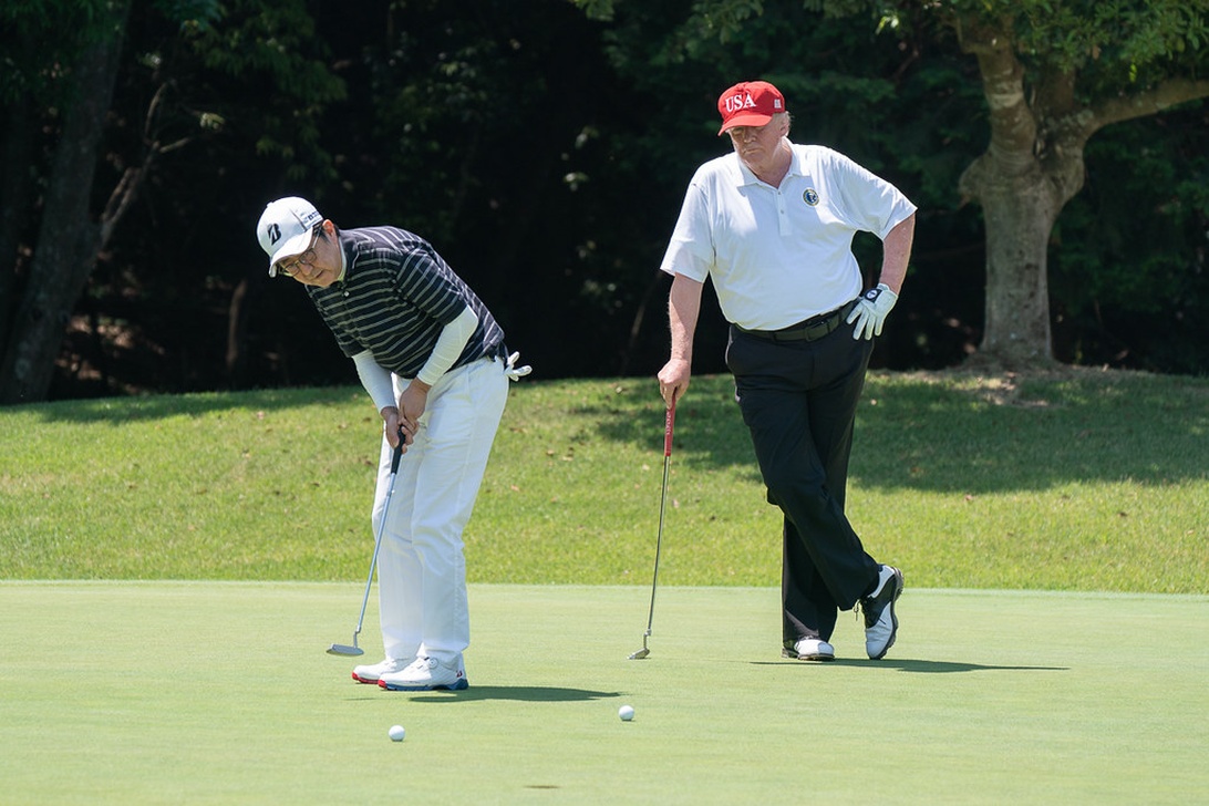 Golfspelare lagar ett nedslagsmärke på greenen med en greenlagare.
